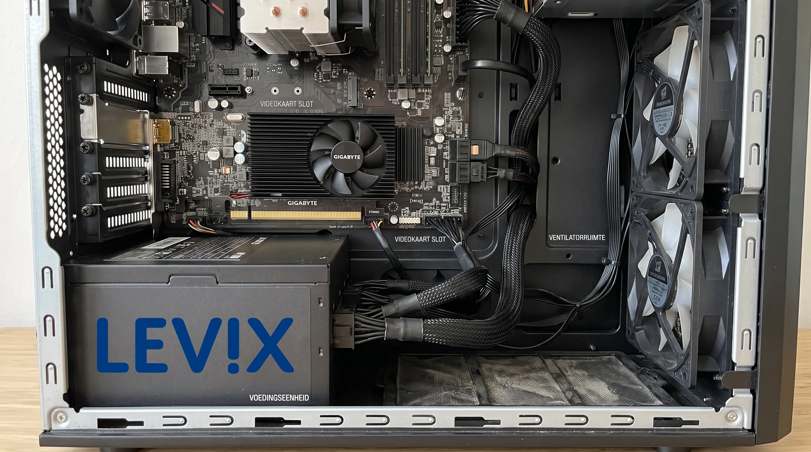 Een geopende desktop-pc toont de geplaatste videokaart, de voeding met aangesloten kabels en de vrije ruimte tot de ventilatoren van de behuizing.