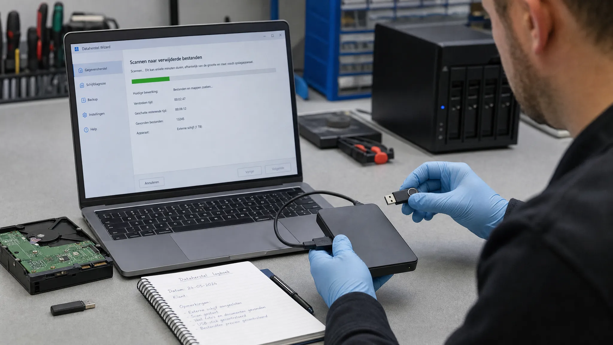 Een open laptop op een werkbank naast een externe harde schijf, USB-stick en notitieblok, terwijl een technicus de opslagmedia zorgvuldig controleert voor dataherstel.